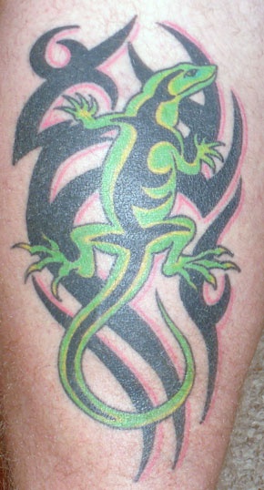 a lizard tattoo is on the leg of a man's legs, which are covered in black and green ink