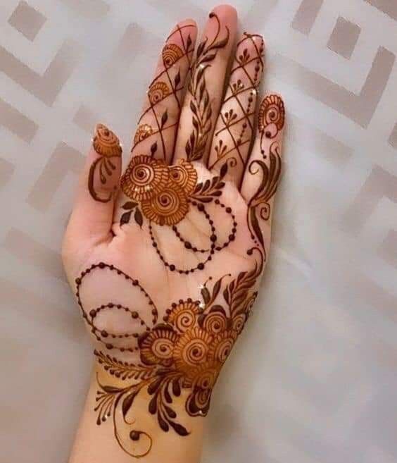 a woman's hand with henna tattoos on it and an intricate design in the middle