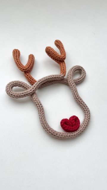 a crocheted reindeer head with a red heart on it's antlers