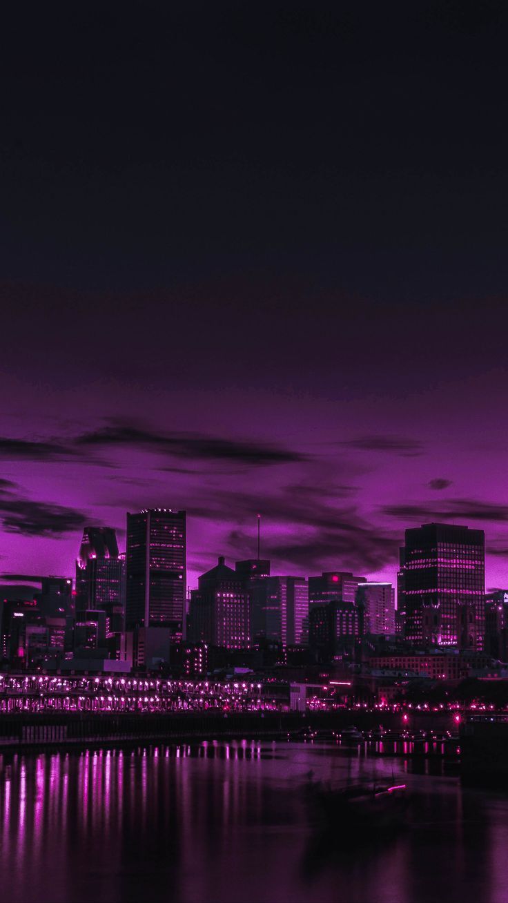 the city skyline is lit up in pink and purple