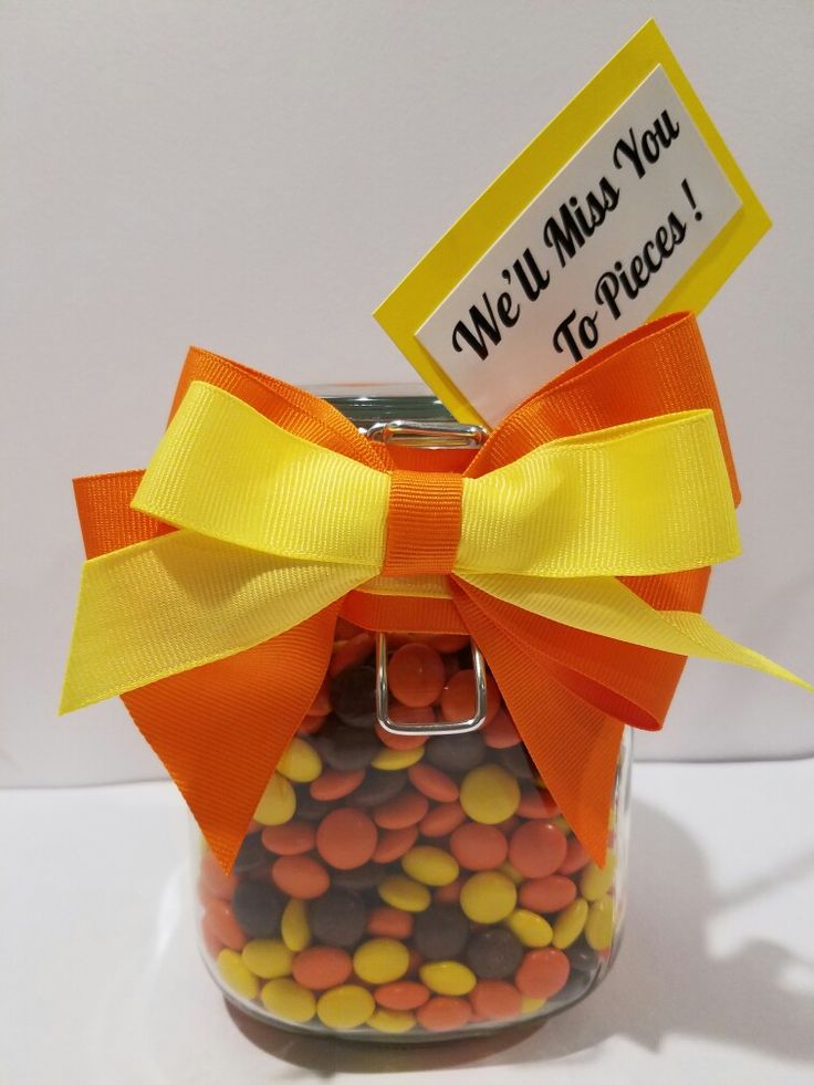 a jar filled with candy sitting on top of a white table next to a sign