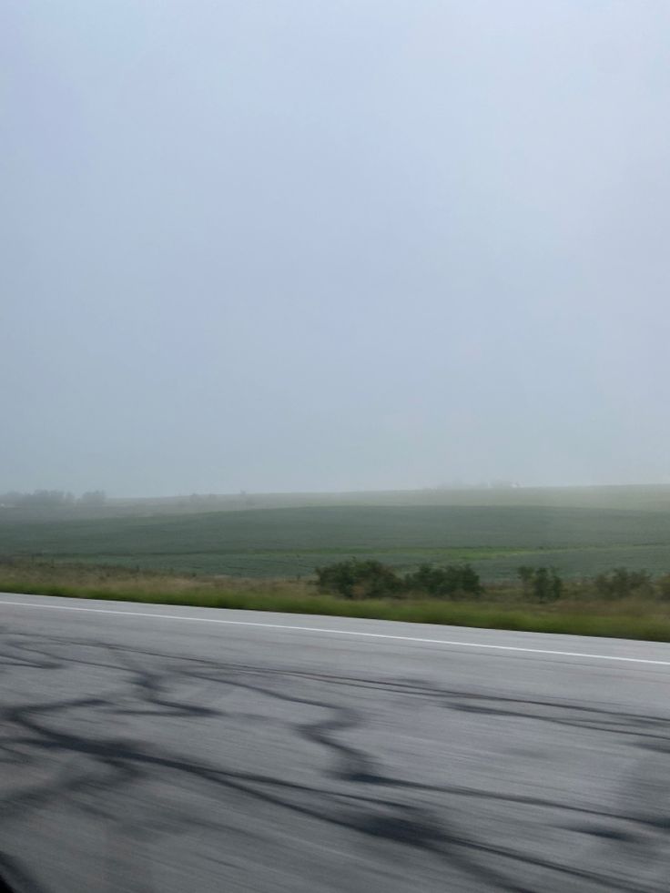 an empty highway with no cars on it in the middle of the day and foggy sky