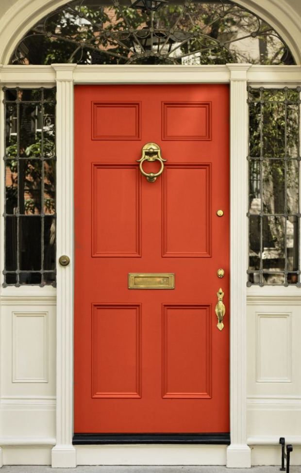 an orange door with white trim and gold hardware