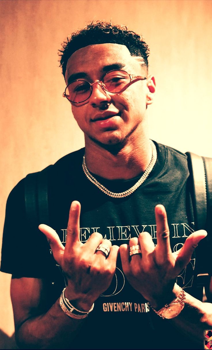 a young man wearing glasses making the vulcan sign with his hands while standing in front of a wall