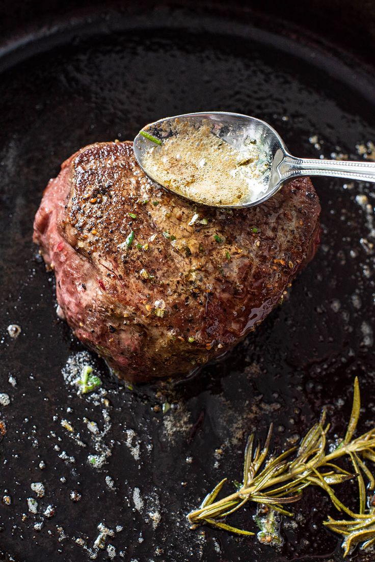 a piece of meat with a spoon in it sitting on top of a skillet