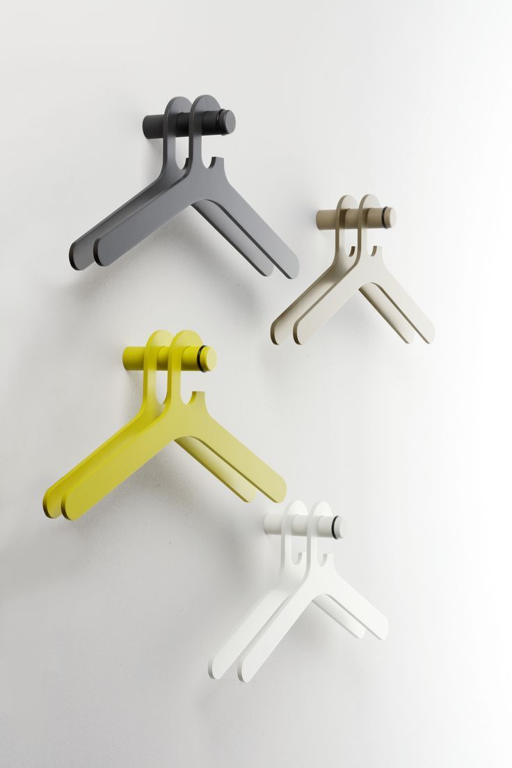 four different colored clothes hangers on a white wall