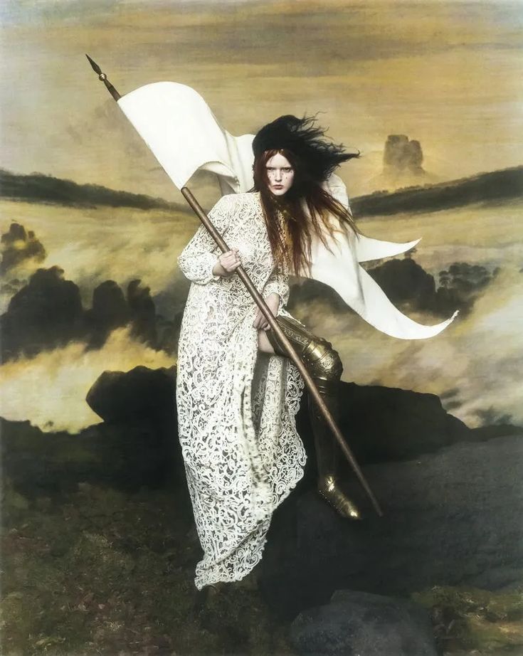 a woman with long hair holding a white flag and standing in front of a painting