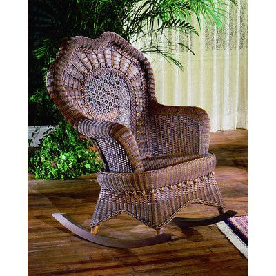 a wicker rocking chair sitting on top of a wooden floor next to a potted plant