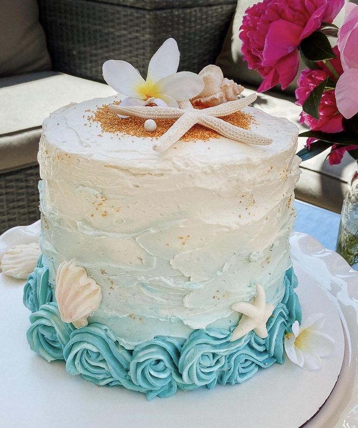 a white cake with blue icing and starfish decorations on top is sitting on a table