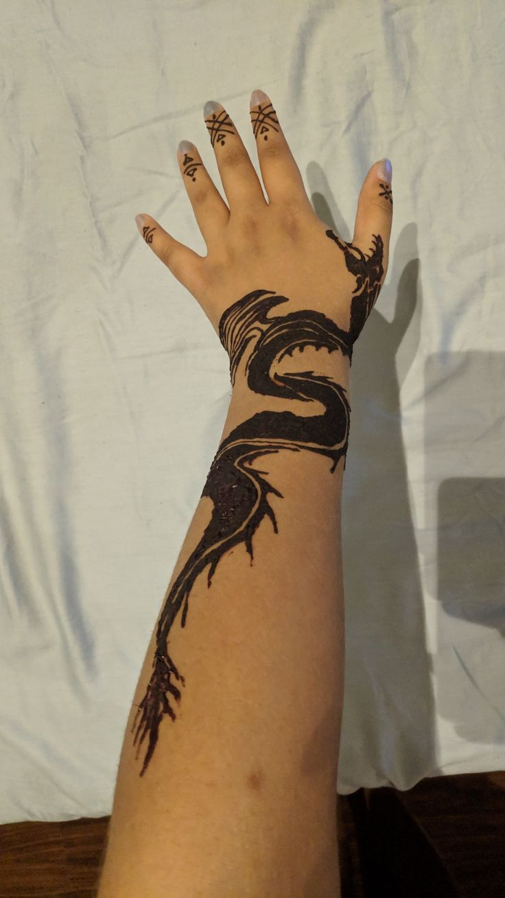 a woman's arm with a tattoo on it and her hand in the shape of a dragon