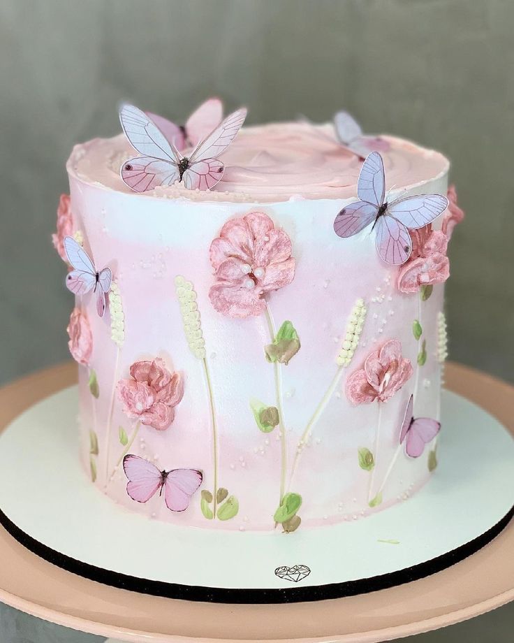 a pink cake decorated with butterflies and flowers