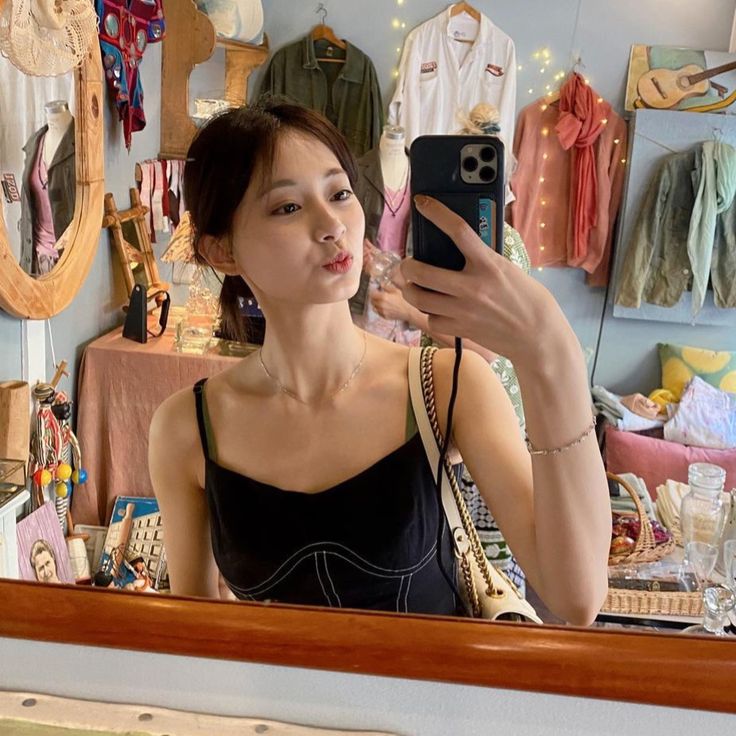 a young woman taking a selfie in front of a mirror with her cell phone