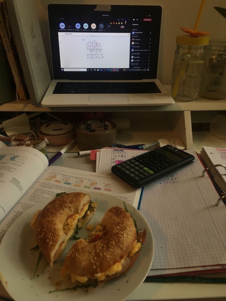 a sandwich is on a plate next to an open book and a calculator