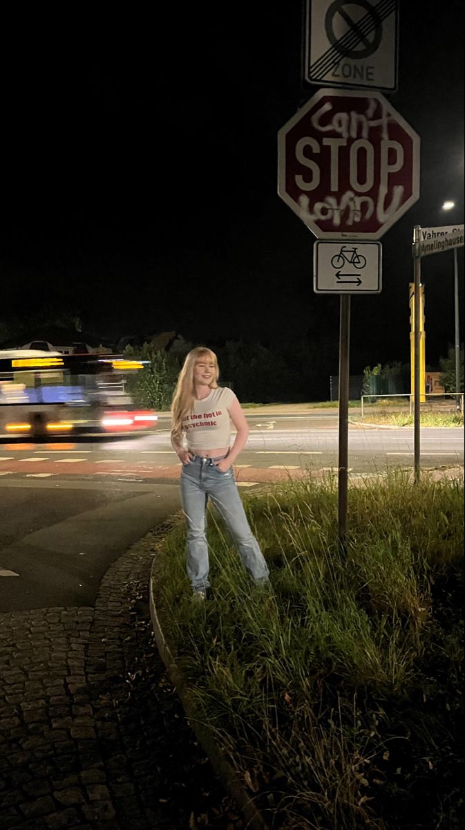 a woman standing next to a stop sign at night