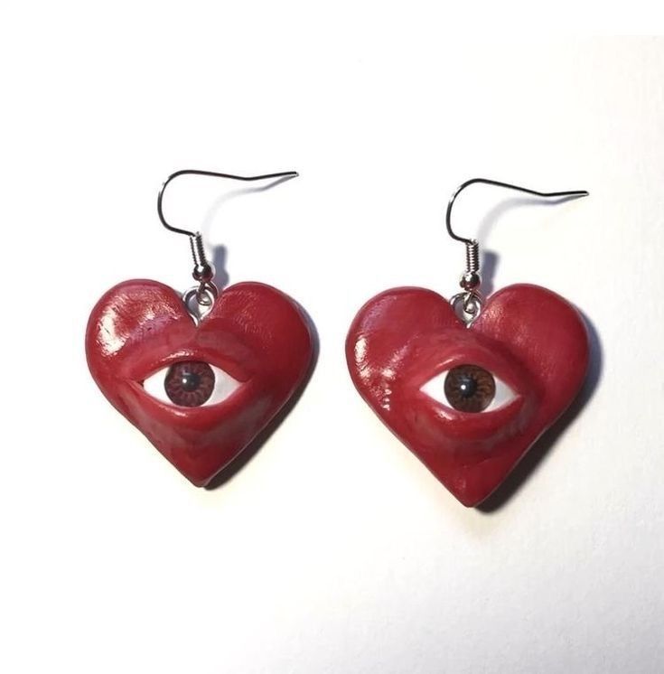 two red heart shaped earrings with an eye on them