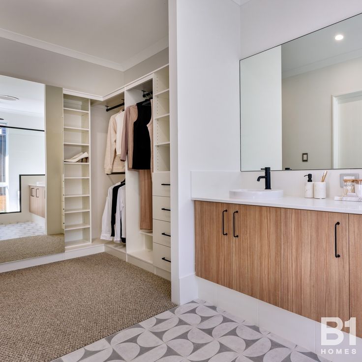 a walk in closet with two sinks and open shelving units on either side of the room