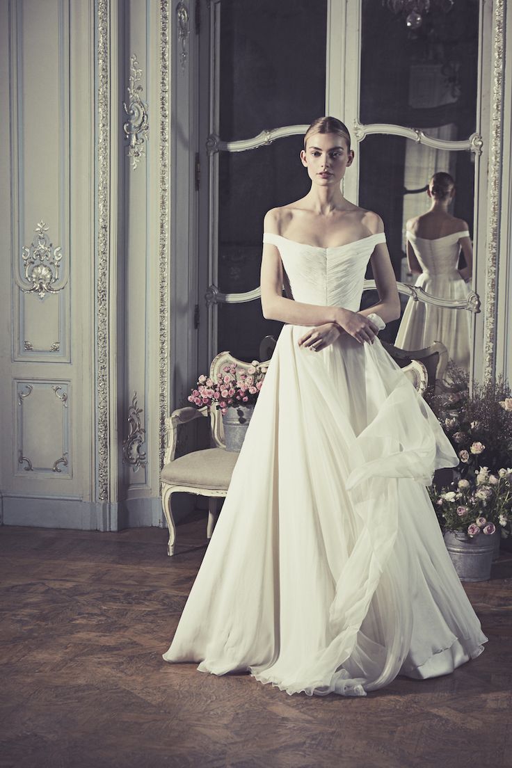 a woman in a white wedding dress standing next to a mirror