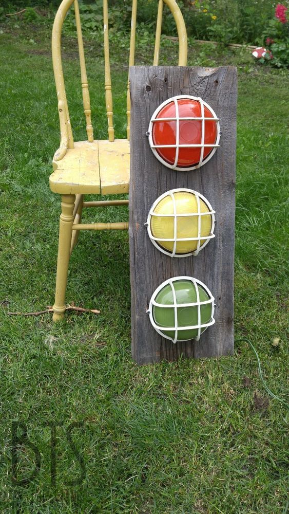 a chair sitting in the grass next to a wooden sign with different colored balls on it