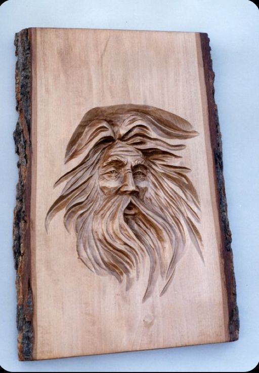 a wood carving of a bearded man's face on a piece of plywood