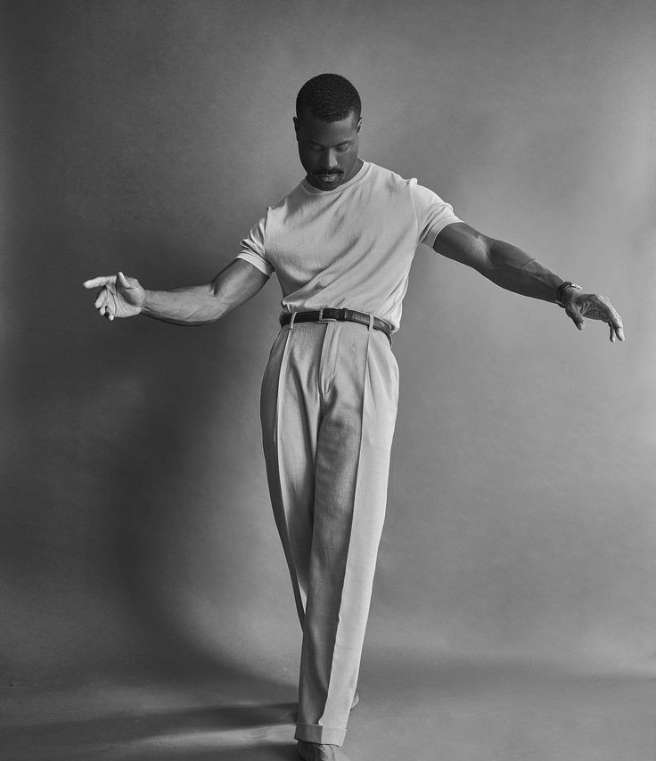 a man in white shirt and pants standing on one leg with his hands out to the side