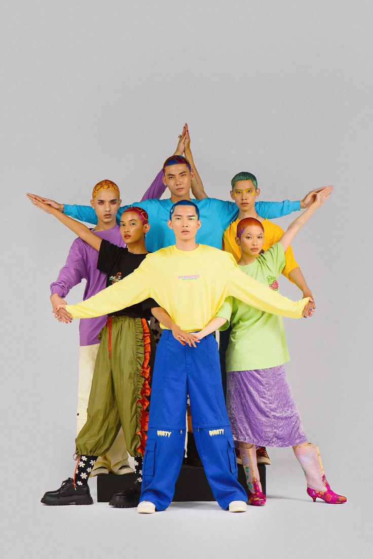 a group of people standing next to each other in front of a white background with one person holding the arms out