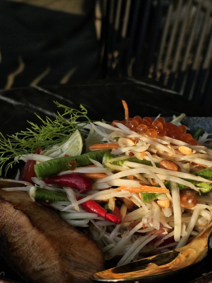 a salad with carrots, celery and other vegetables on a black plate