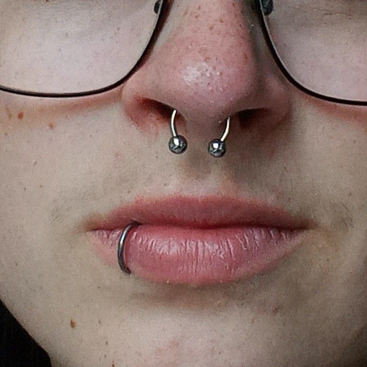 a woman wearing glasses and nose piercings