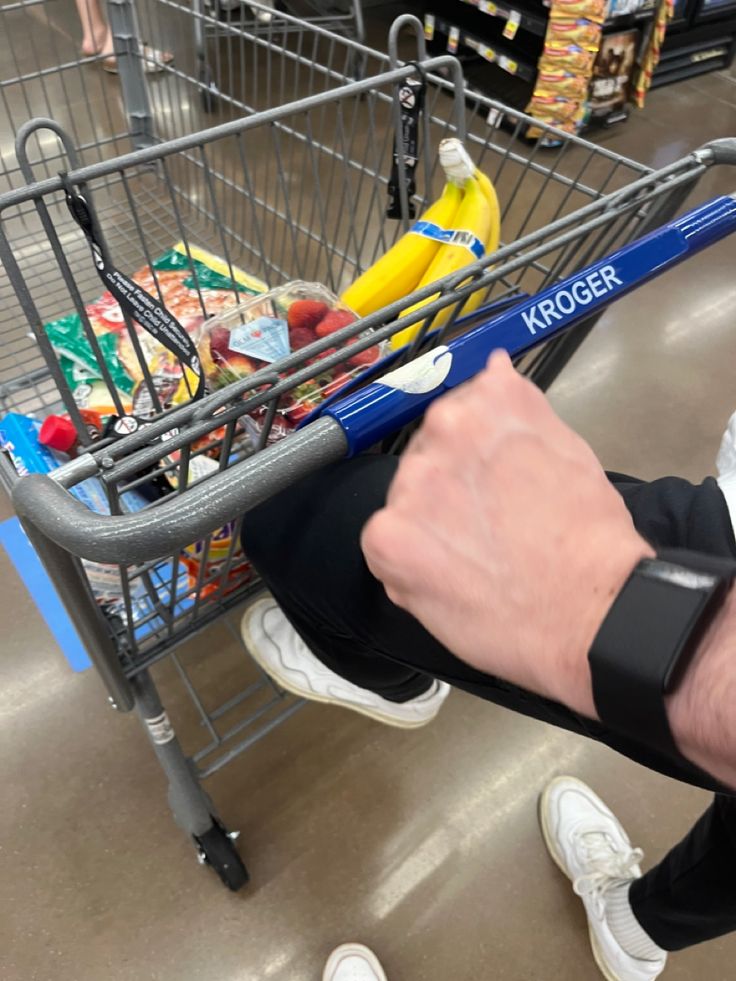 a person sitting in a shopping cart with their arm wrapped around the handle, holding onto an item