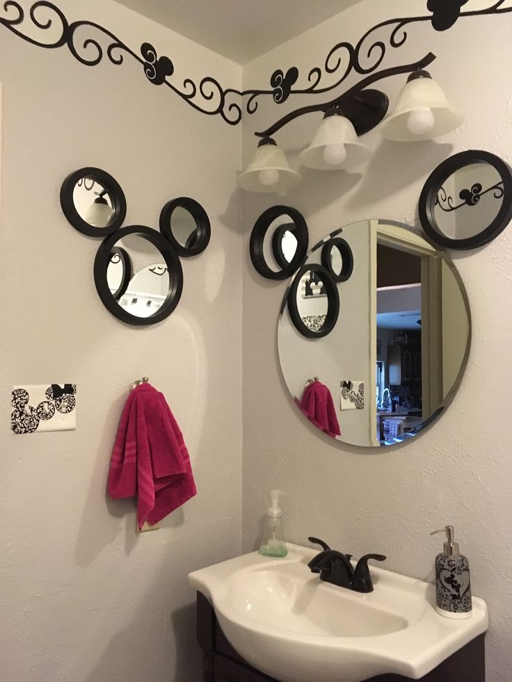 a bathroom with mickey mouse mirrors on the wall and a sink in front of it