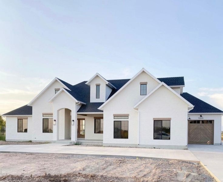 a large white house sitting on top of a dirt field