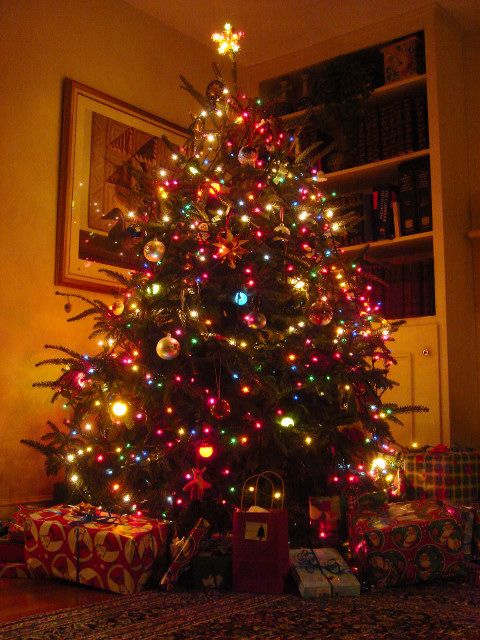 a lit christmas tree with presents under it