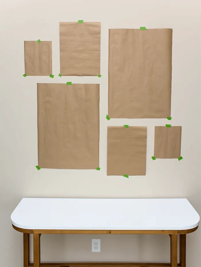 several pieces of brown paper taped to the wall above a white table with green tape on it