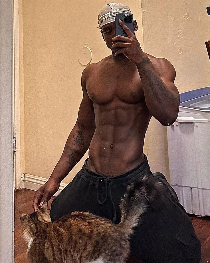 a shirtless man taking a selfie with his cat