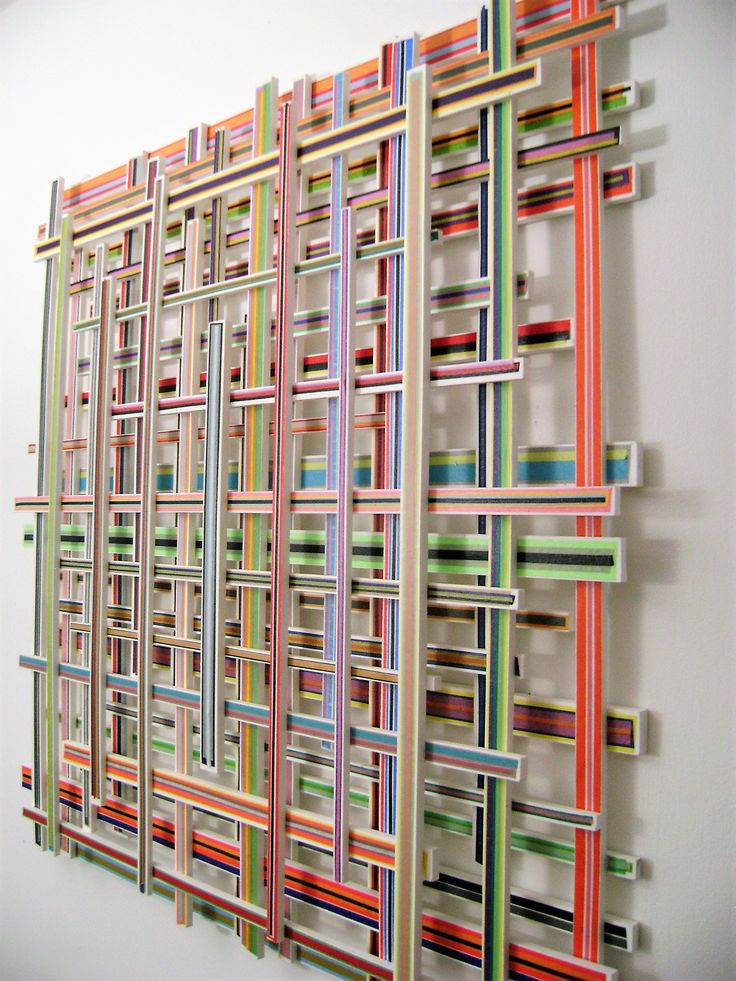 an art piece made out of strips of colored paper on a wall next to a white wall