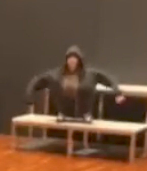 a blurry image of a person sitting on a bench in front of a wall