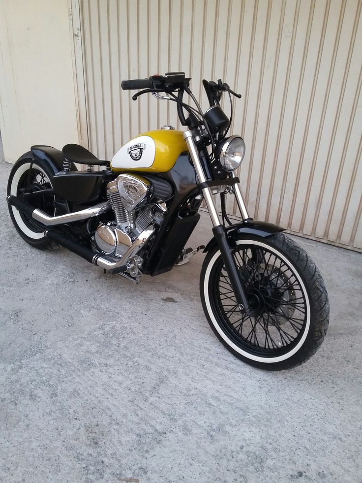 a yellow and black motorcycle parked in front of a garage door with no one on it