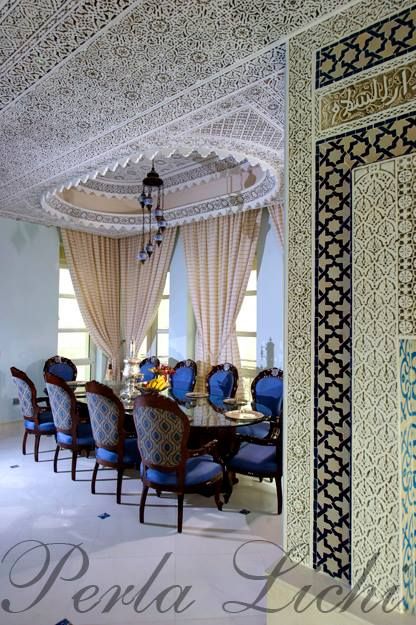 an ornate dining room with blue upholstered chairs and intricately designed wall coverings