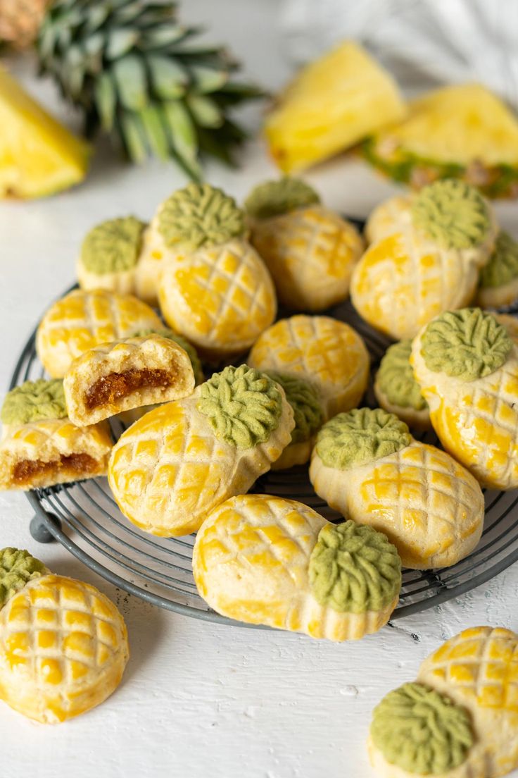 some yellow and green cookies are on a metal plate with pineapples in the background