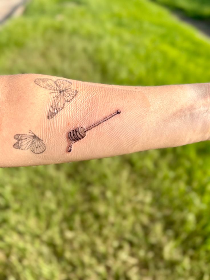 a person's arm with tattoos on it and a butterfly in the middle of the arm