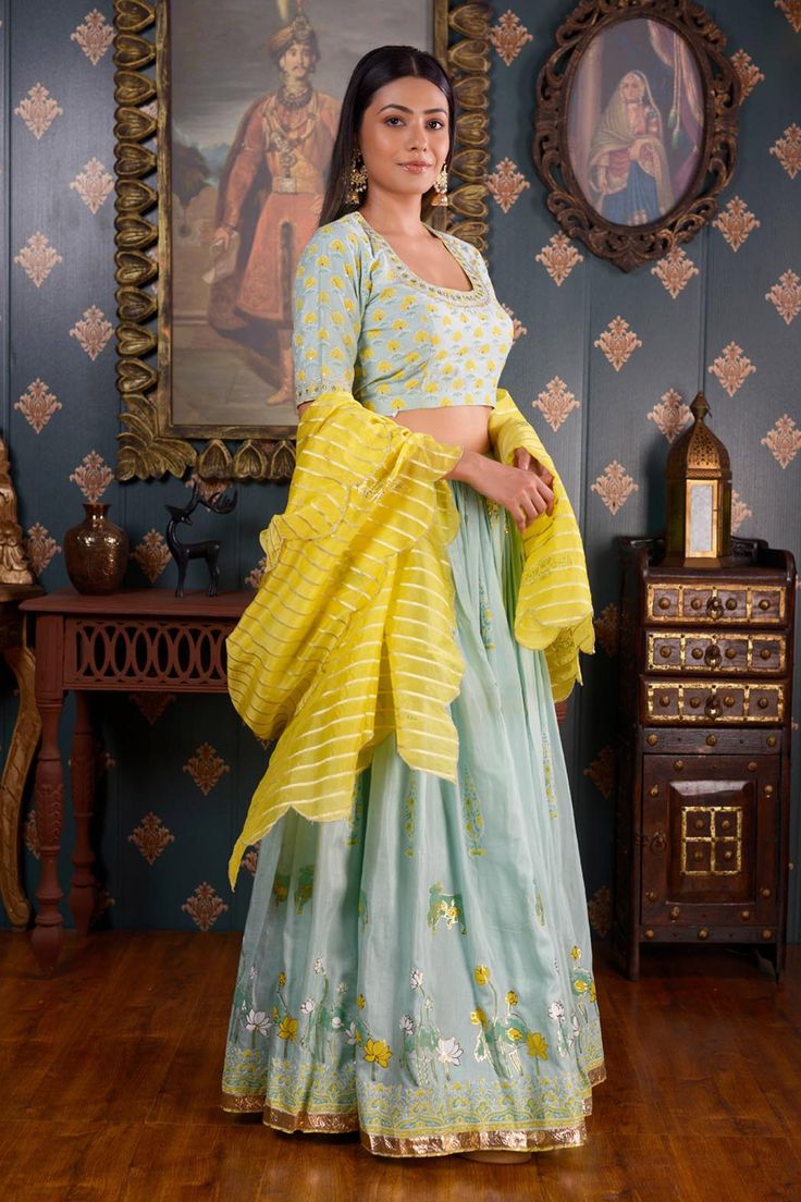 Sea green lehenga with foil printed floral motifs and gota patti border. Comes with mirror embroidered blouse and striped yellow dupatta.
Component: 3
Pattern: Print and Embroidery
Type Of Work: Foil Print, Gota Patti, Mirror and Sequin
Neckline: Scoop
Sleeve Type: Half
Fabric: Cotton Silk
Color: Green
Other Details: 
Striped dupatta with scalloped border
Mirror embroidery on the neckline
Closure: Blouse: Side zip
Occasion: Sangeet - Aza Fashions Sea Green Lehenga, Yellow Dupatta, Print Lehenga, Mirror Embroidery, Print And Embroidery, Green Lehenga, Scalloped Border, Foil Print, Sea Green