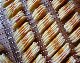 some cookies with icing and oranges on a cooling rack in front of them