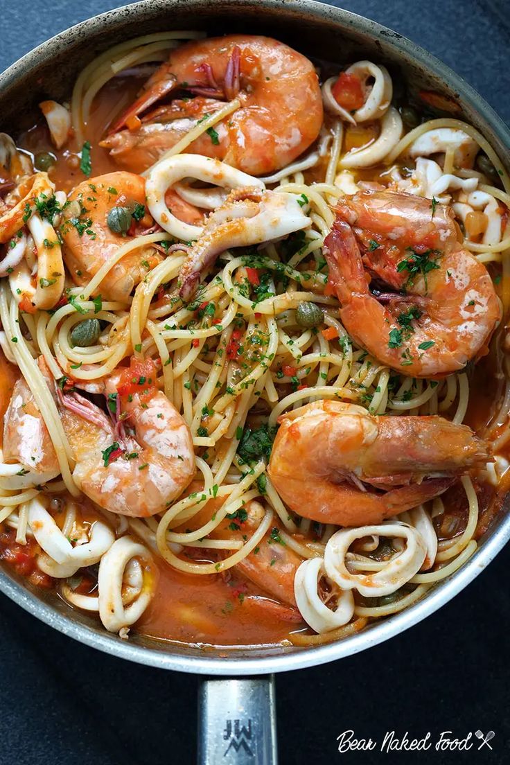 pasta with shrimp and tomato sauce in a skillet on a blue countertop, ready to be eaten