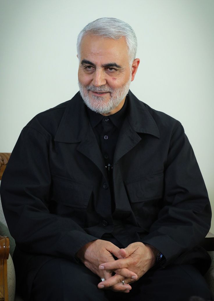 an older man sitting in a chair with his hands crossed