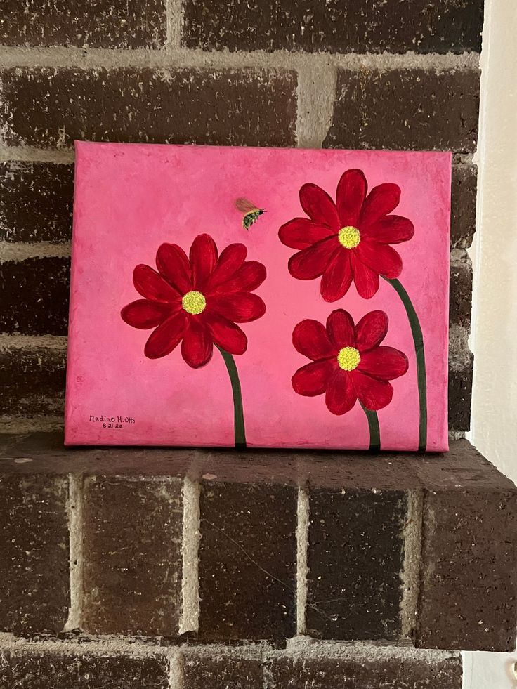 a painting on a brick wall with red flowers and a bee in the middle,