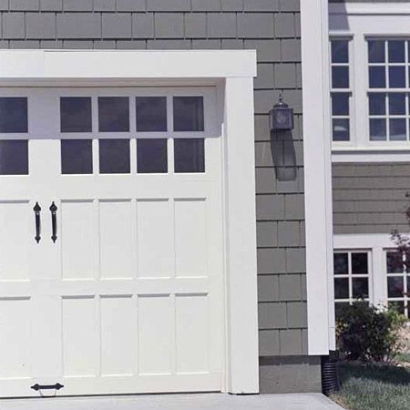 a white garage door in front of a gray house