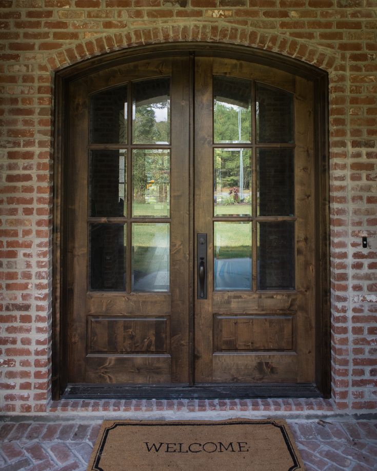 a welcome mat sits in front of a wooden door with glass panes on it