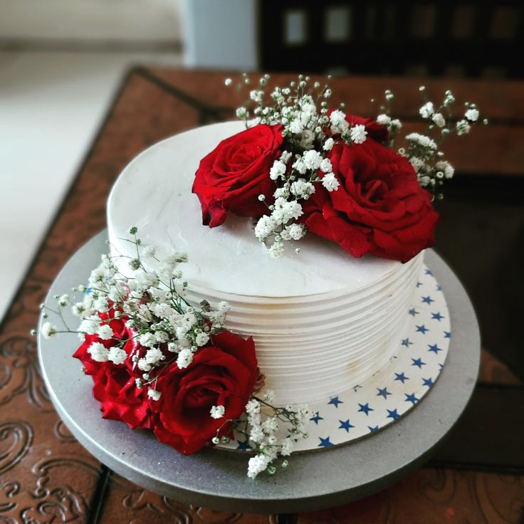 a white cake topped with red roses and baby's breath