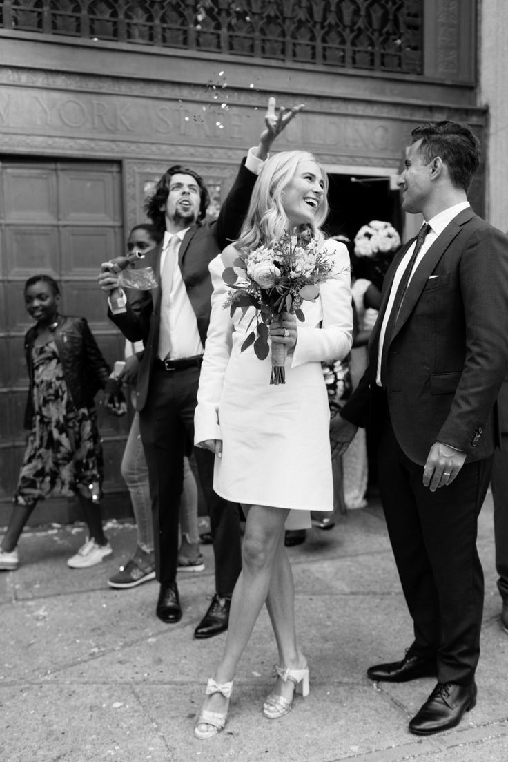 a man and woman are standing in front of a building with confetti falling from their hands