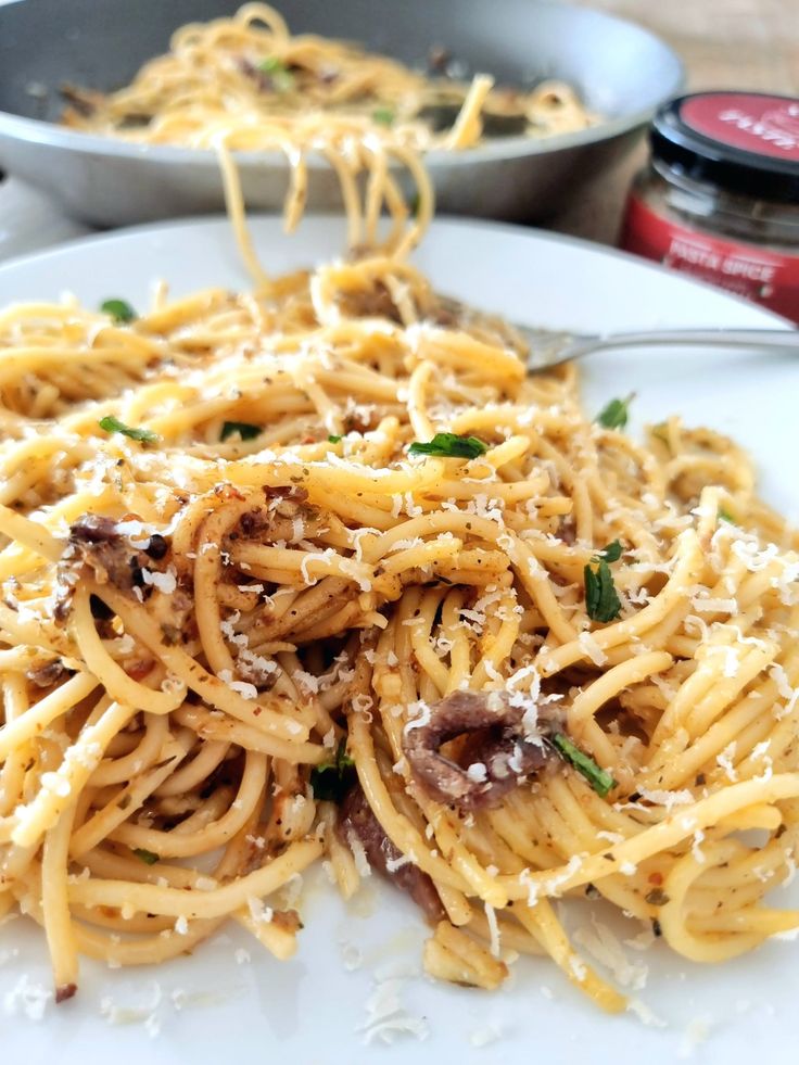 pasta with mushrooms and parmesan cheese is served on a white plate, ready to be eaten