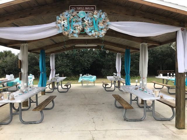 an outdoor picnic area with tables and benches under a canopy covered in white drapes